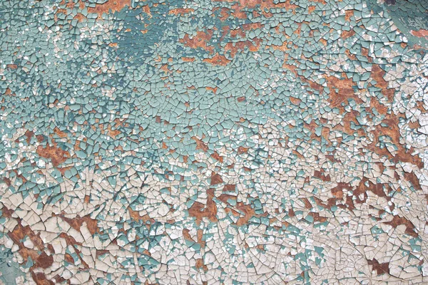 Background and texture of an old weathered car door with paint peeling off. You can see the rust peeking out from under the paint.