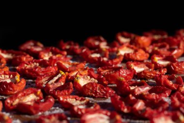 Close up and background of tomatoes lying in the sun to dry. the background is black.