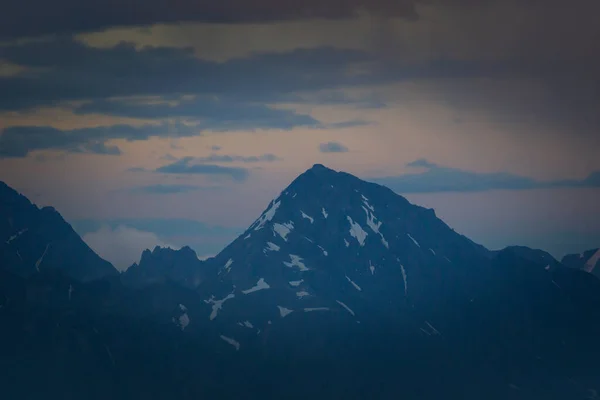 Gama de montanhas com silhuetas visíveis através da névoa colorida da manhã. — Fotografia de Stock