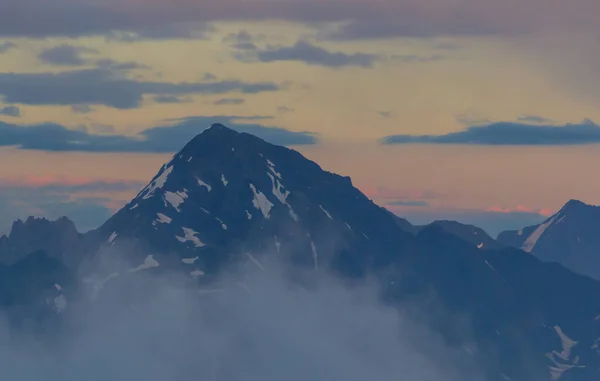 Bergkette mit sichtbaren Silhouetten durch den morgendlichen bunten Nebel. Stockbild