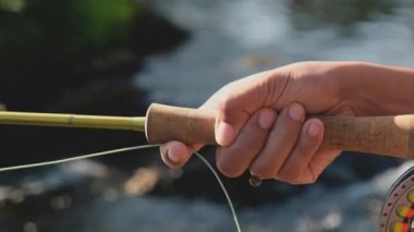 Genç bir Asyalı kadının eli, nehirde sineklerin oltasını koparıyor.