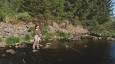 Genç bir Asyalı dişi sinek yaz akşamında nehirde balık tutuyor.