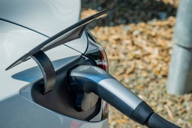 Gümüş elektrikli araç şarj prizi, elektrikli araba prizine takılmış.