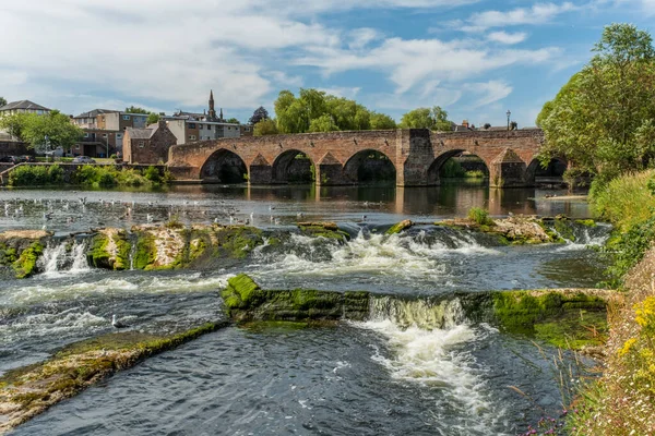 Dumfries 'deki Caul Weir' ın üzerinden akan Nith Nehri, arka planda Ortaçağ Devorgilla Köprüsü, Dumfries ve Galloway, İskoçya