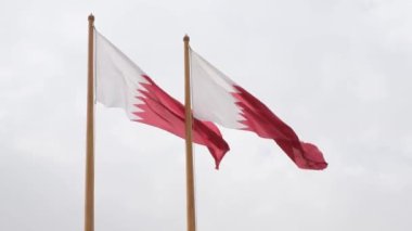 Katar 'ın iki Al-Adaam bayrağı Doha, Katar üzerinde gökyüzünde dalgalanıyor.
