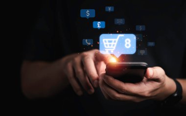 İş adamı elinde alışveriş arabasıyla online alışveriş konseptine yeni bir sipariş vermek için akıllı telefon tutuyor..