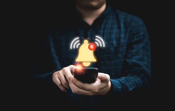Uygulama uyarı konsepti için çalan sanal sarı zilli akıllı telefonu tutan bir iş adamı..