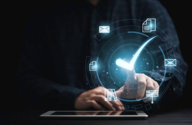 Sanal belge taşıyan bir işadamı elinde tablet tutuyor ve çevrimiçi onaylı kağıtsız ve kalite güvencesi kavramı için doğru işareti işaretliyor.