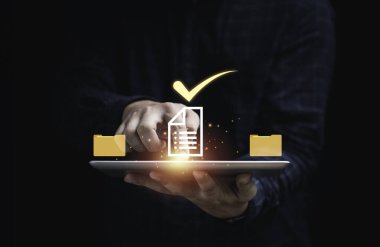 Sanal belge taşıyan bir işadamı elinde tablet tutuyor ve çevrimiçi onaylı kağıtsız ve kalite güvencesi kavramı için doğru işareti işaretliyor.