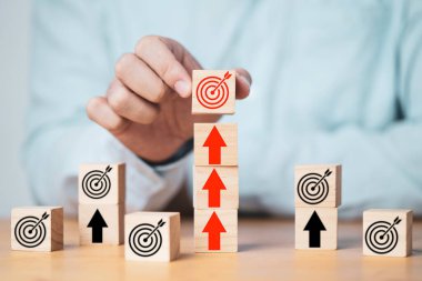 İş adamı hedef tahtasını tahta bloğa ekran yazdıran oklar üzerine koyuyor, iş kurma başarısı hedefleme kavramının artması ve meydan okuması.