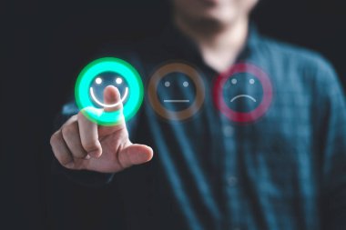 İş adamı, müşteri değerlendirmesi için gülen yüz simgesi ve kullanım ürünü ve servis kavramından sonra müşteri memnuniyeti için akıllı telefon kullanır.