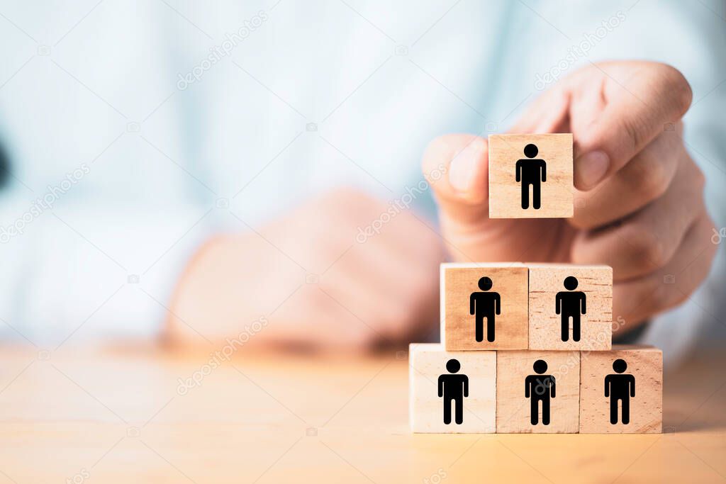 Businessman holding and stacking wooden cube block which print screen human icon for sport teamwork and business corporation concept.