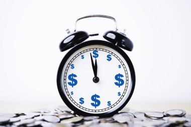 Zaman ve para yönetimi kavramı için para yığınının üzerindeki alarm saati içindeki dolar işareti ekranı.
