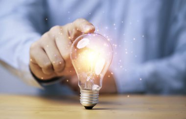 Yaratıcı düşünce ve problem çözme konsepti için parlayan lambaya ya da ampule elle dokunmak.