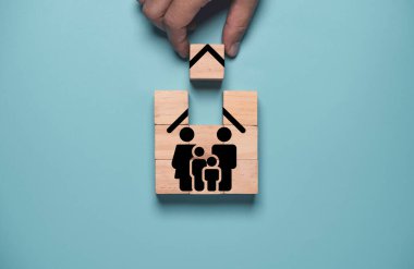 Hand holding wooden cube block to complete assemble family insurance icon Insurance is important for managing risk that may occur in the future both ourselves and our family concept.