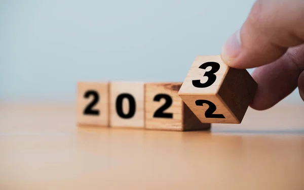 Değişiklik ve hazırlık için 2022 ile 2023 yılları arasında çeviren tahta blok küpü Mutlu Noeller ve mutlu yıllar..