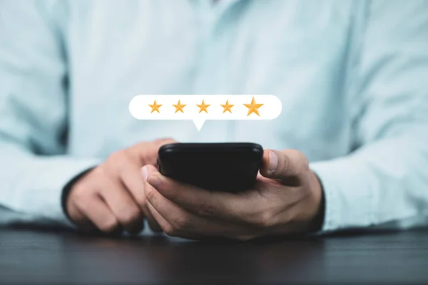 Businessman holding smartphone to give five yellow stars , Excellent customer satisfaction and evaluation for good quality product and service concept.