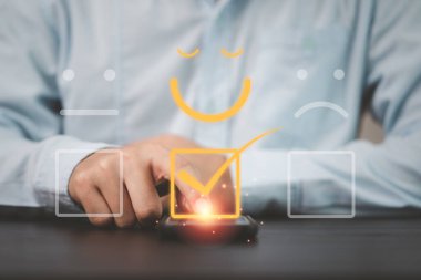 İş adamı, müşteri değerlendirmesi için gülen yüz simgesi ve kullanım ürünü ve servis kavramından sonra müşteri memnuniyeti için akıllı telefon kullanır.
