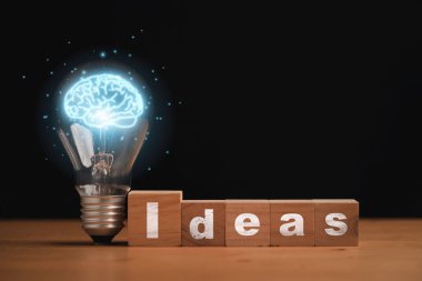 Virtual blue brain inside of lightbulb with Idea wording on wooden cube block for creative thinking idea and problem solving after study knowledge concept.