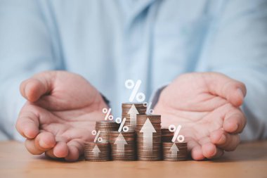 Two hand giving heap of coins money with up arrow and percentage symbol for financial banking increase interest rate or mortgage investment dividend from business growth concept.