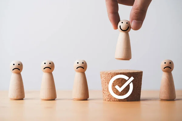 Hand holding smile wooden figure to above of wooden cube with correct sign mark which higher position for approve promotion from staff to management and human development concept.