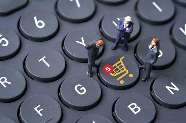 Businessmen miniature figure standing on computer keyboard with shopping trolley cart and notification for online shopping and e-commerce business concept.