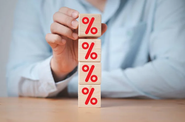 Businessman stacking red percentage sign on wooden cube block for financial planing of interest rate and mortgage ranking concept.
