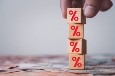 Hand stacking red percentage sign symbol on wooden cube block for financial increase interest rating and dividend from investment growth concept.