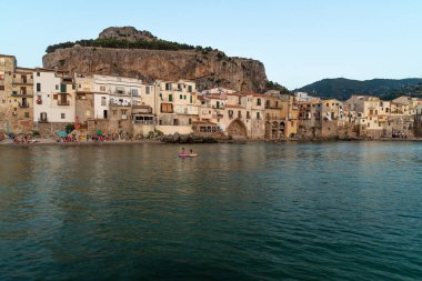 Sicilya 'daki Cefalu kasabasının gün batımında turistlerle ve tipik evlerle manzarası.