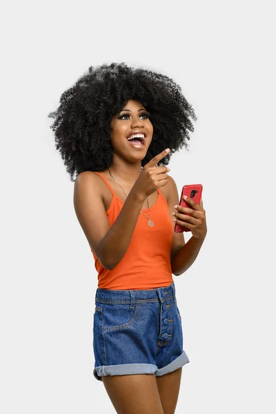 Ung Kvinna Med Afro Frisyr Innehav Mobiltelefon Isolerad Grå Bakgrund — Stockfoto