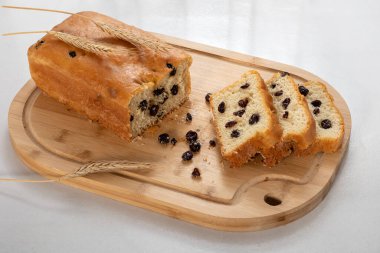 Ev yapımı ekmek, kuru üzüm, tahta tahtada bir dilim ekmek, beyaz arka planda.