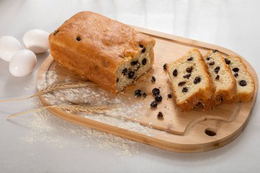 Ev yapımı ekmek, kuru üzüm, tahta tahtada bir dilim ekmek, beyaz arka planda.