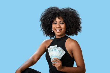  Elinde Brezilya 'ya ait para banknotları olan gülümseyen kadın, kesinlikle şaşırdı. Mesaj, insan, reklam konsepti, mavi arka planda izole edilmiş..