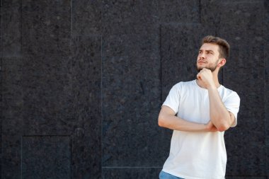 Duygular, jest, ifade ve insan konsepti beyaz tişörtlü ve kot pantolonlu düşünceli beyaz sakallı bir adam bir elini yüzüne dayayıp siyah arka plandaki fotokopi odasına bakıyor.