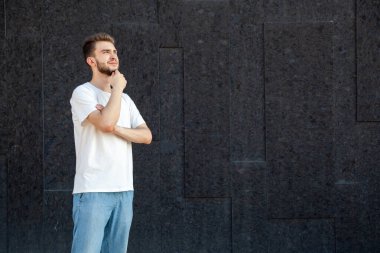 Duygular, jest, ifade ve insan konsepti beyaz tişörtlü ve kot pantolonlu düşünceli beyaz sakallı bir adam dışarıda, siyah arka planda fotokopi odasına bakıyor.