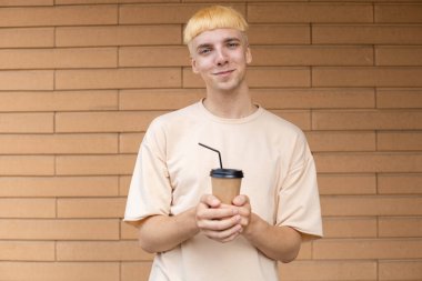 İçkiler, yaşam tarzı, tüketim ve insan konsepti - bej tişört giyen Avrupalı bir adam, elinde siyah kapaklı bir fincan kahve ve iki elinde de kamışla bir duvar arkasında fotokopi alanı olan bir kamış.