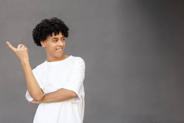 Jest, duygu, ifade ve insan konsepti. Gülümseyen Amerikalı adam parmağını gösteriyor, beyaz tişört giyiyor ve arka plandaki fotokopi odasına bakıyor.