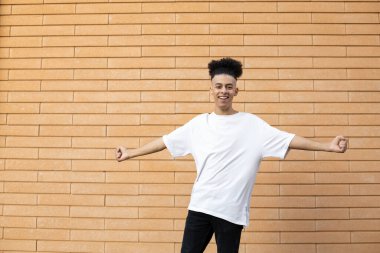 Yarışmayı kazanan, beyaz tişört ve siyah kot pantolon giyen ve fotokopi çekilen duvardaki kameraya bakan mutlu bir Afro-Amerikalı.