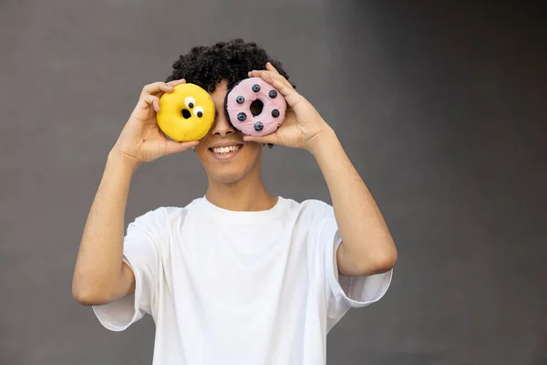 娱乐和人的概念 快乐的非裔美国人用黄色和粉色甜甜圈做脸和眼睛 灰色背景上穿着一件带有复制空间的白色T恤 — 图库照片