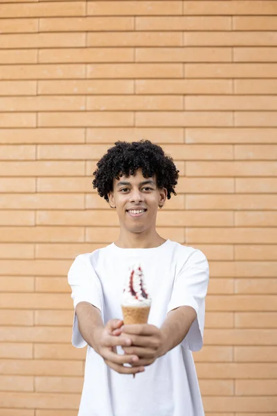 垃圾食品和人的概念 年轻的卷发美国人 双手托着一个白色的冰激凌锥 穿着一件白色的T恤衫在砖墙的背景上 — 图库照片