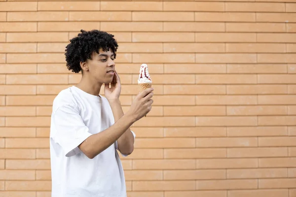 垃圾食品和人的概念 站在一旁 一个心事重重的美国人拿着红色果酱冰淇淋 穿着白色T恤衫 挂在砖墙上 有抄袭的空间 — 图库照片