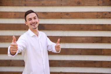 Yaşam tarzı, duygular, jest ve insan konsepti - gülümseyen sakallı beyaz adam, göz kırpıyor, işaret ediyor ve fotokopi çekilen kahverengi başlıklı arka planda kameraya bakıyor