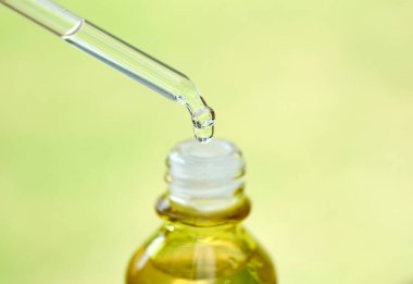 Yüzün serum kolajen nemlendiricisini açık sarı şişe yumuşak ışık arka planına döküyorum. Koruyucu cilt bakımı yüz özü yağı, C vitamini güzellik ve kaplıca konsepti..
