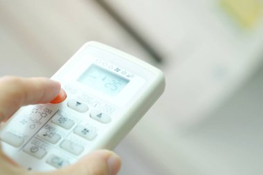 Adamın eli uzaktan kumanda ile açılıyor klima yatak odasında 25 santigrat dereceye kadar soğutuluyor. Sağlık kavramları ve enerji tasarrufları