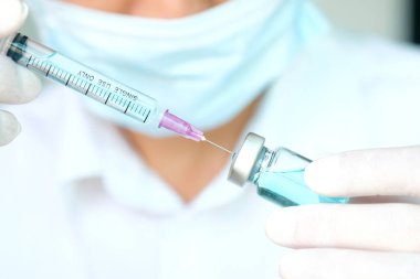 Şırınga ve ilaç şişesini tutan doktorun eli. Enjeksiyon için hazırlanılıyor