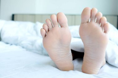 Güzel bacakları ve ayakları Evdeki yatak odasında battaniyenin altında mutlu bir şekilde uyuyor..
