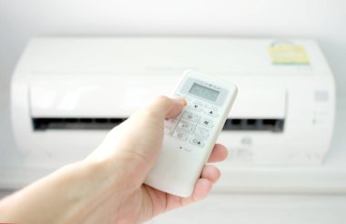 Adamın eli uzaktan kumanda ile açılıyor klima yatak odasında 25 santigrat dereceye kadar soğutuluyor. Sağlık kavramları ve enerji tasarrufları