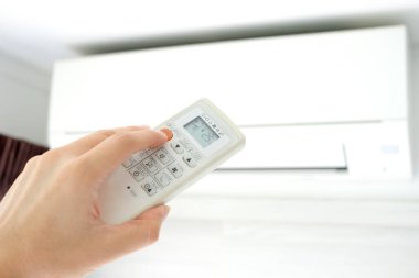 Adamın eli uzaktan kumanda ile açılıyor klima yatak odasında 25 santigrat dereceye kadar soğutuluyor. Sağlık kavramları ve enerji tasarrufları