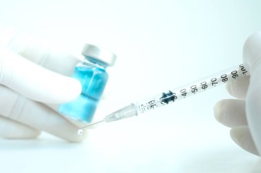 Şırınga ve ilaç şişesini tutan doktorun eli. Enjeksiyon için hazırlanılıyor