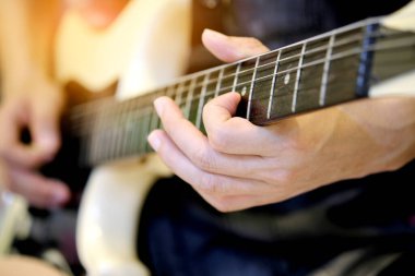 Bir adam, müzik odasında mutlu bir şekilde elektro gitar çalıyor.